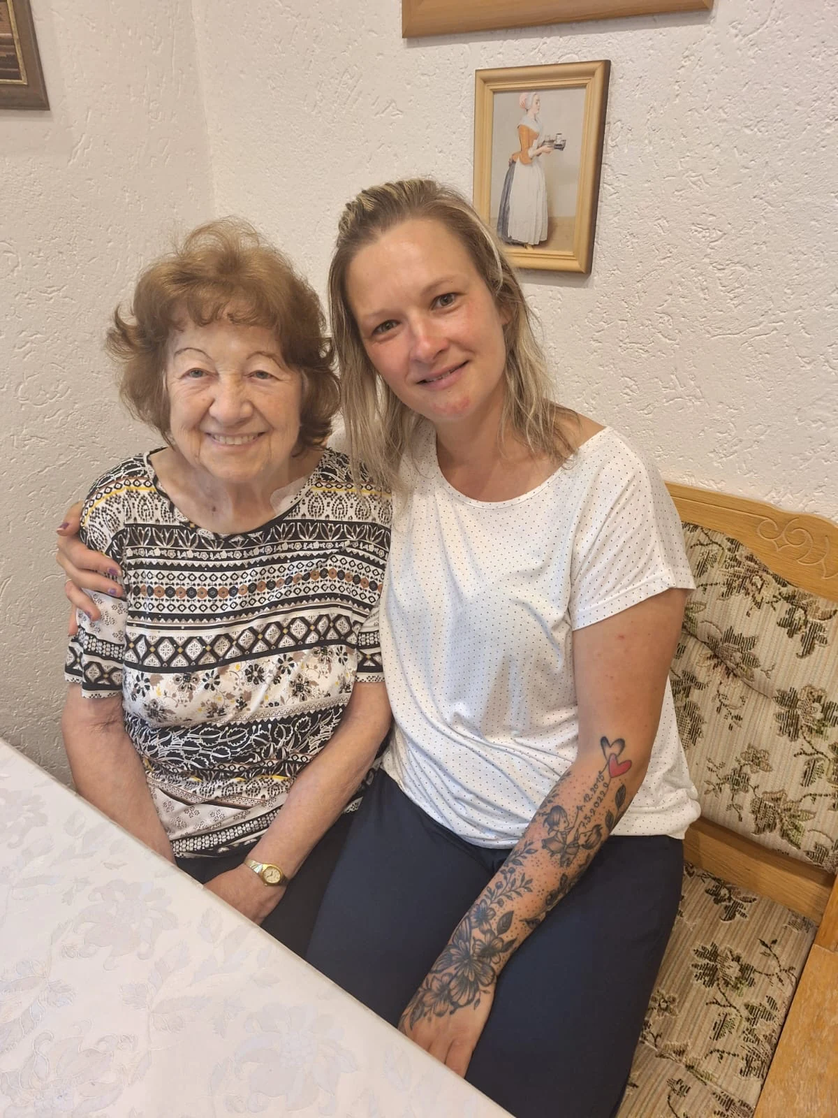 Ingrid Plöttner und ihre Alltagsbegleiterin Anika sitzen lächelnd nebeneinander.