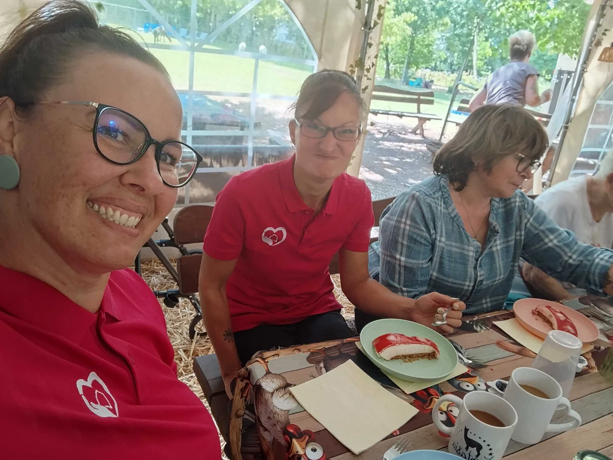 Begleiterinnen und Klientinnen sitzen zusammen bei Kaffee und Kuchen.