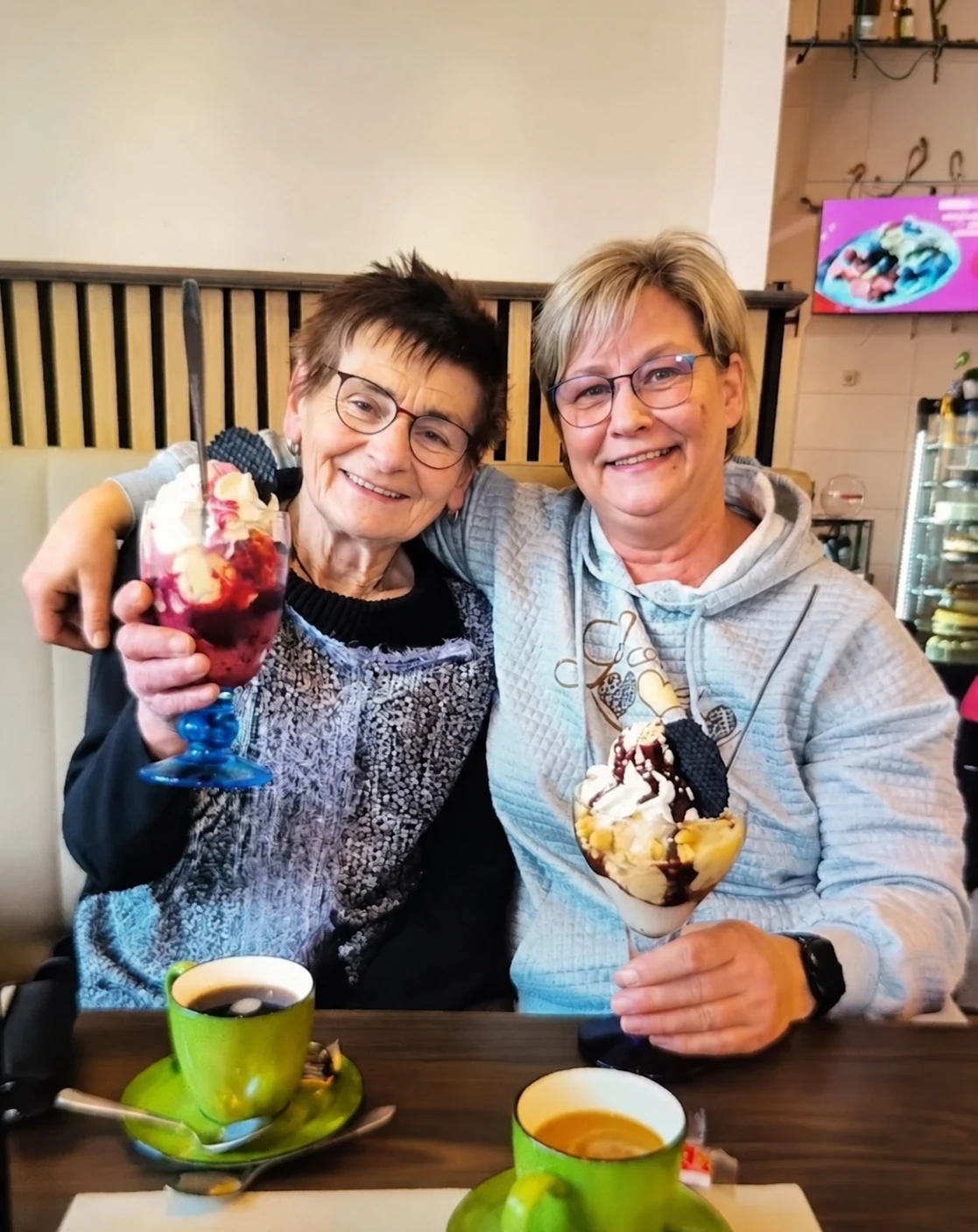 Frau Wolf und ihre Begleiterin Sandra sitzen mit Eisbechern im Café.