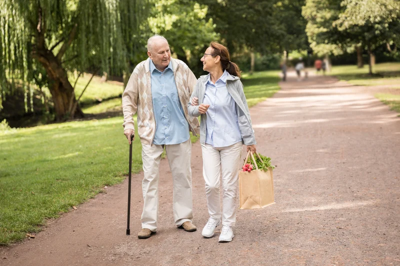 Ein älterer Mann und eine Frau sind gemeinsam im Grünen unterwegs.
