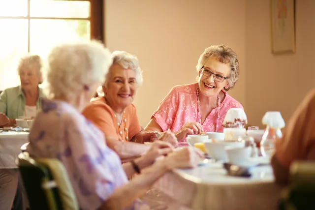 Mehrere ältere Frauen unterhalten sich bei Kaffee am Tisch.