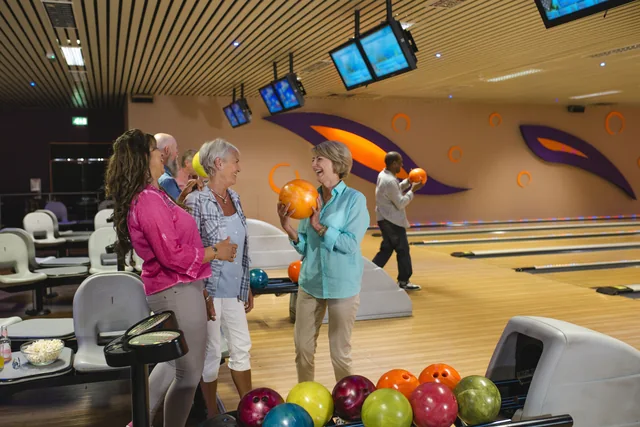 Eine Gruppe älterer Menschen spielt gemeinsam Bowling.