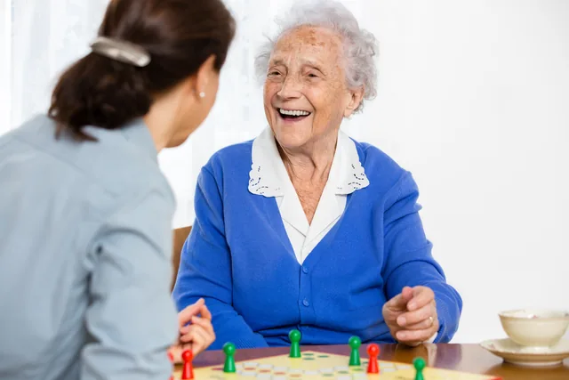 Eine ältere Frau und eine jüngere Frau spielen gemeinsam am Tisch.